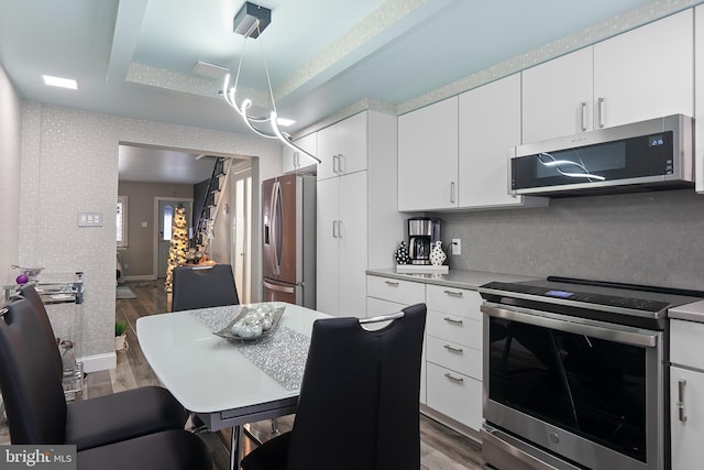 2444 S Percy St, Philadelphia, PA 19148 - kitchen featuring appliances with stainless steel finishes, wood finished floors, wallpapered walls, and white cabinets