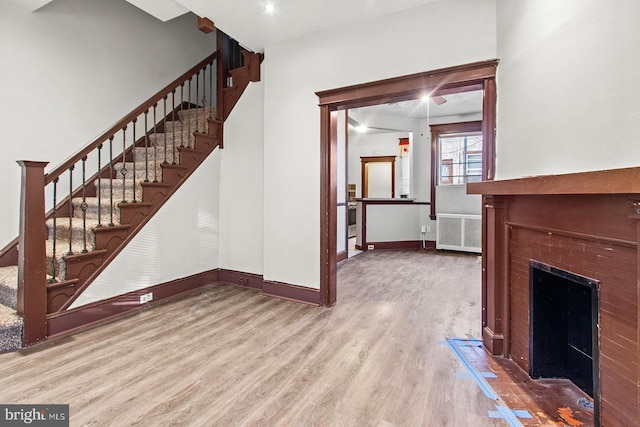 2904 N Taney St, Philadelphia, PA 19132 - unfurnished living room with a fireplace with flush hearth, radiator, wood finished floors, and stairway