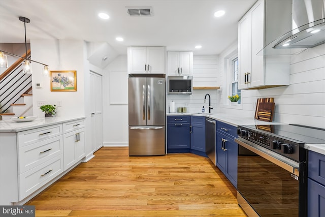 2806 S Abingdon St Unit A, Arlington, VA 22206 - kitchen with appliances with stainless steel finishes, wall chimney range hood, blue cabinetry, white cabinets, and light wood-style flooring