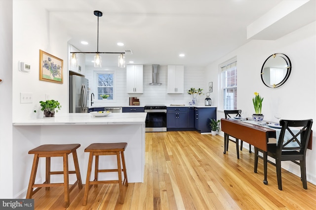 2806 S Abingdon St Unit A, Arlington, VA 22206 - kitchen with stainless steel appliances, wall chimney exhaust hood, blue cabinetry, a breakfast bar area, and healthy amount of natural light