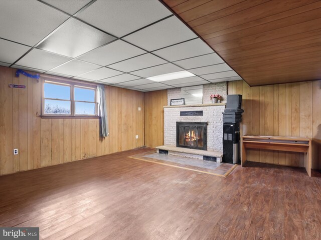 4704 Baughman Ml, Manchester, MD 21102 - unfurnished living room featuring a brick fireplace, wood finished floors, wooden walls, and a paneled ceiling