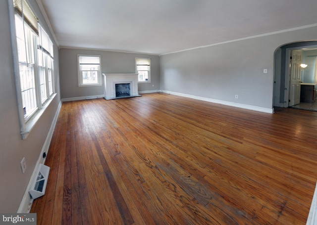 301 E Hanover St, Hanover, PA 17331 - unfurnished living room featuring crown molding, arched walkways, a fireplace with raised hearth, and wood finished floors