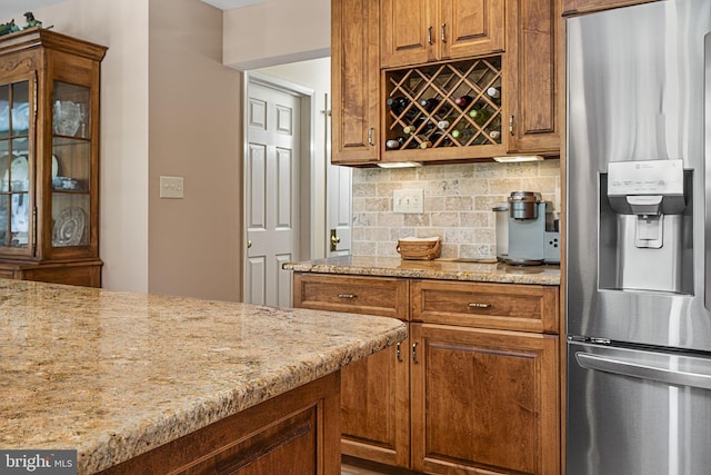 1043 Welsh Ayres Way, Downingtown, PA 19335 - kitchen featuring stainless steel fridge, backsplash, light stone counters, glass insert cabinets, and brown cabinets