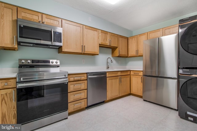 15115 Interlachen Dr Unit 3-1020, Silver Spring, MD 20906 - kitchen featuring appliances with stainless steel finishes, stacked washer / dryer, light countertops, and a textured ceiling