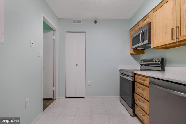 15115 Interlachen Dr Unit 3-1020, Silver Spring, MD 20906 - kitchen featuring appliances with stainless steel finishes, light countertops, light tile patterned flooring, and a textured ceiling