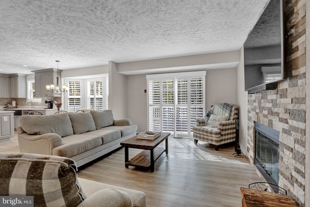 207 Weston Woods Dr, Pasadena, MD 21122 - living area featuring a chandelier, a fireplace, light wood-style floors, and a textured ceiling