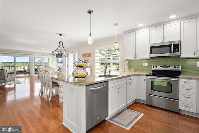 222 N Heron Dr Unit 222-1, Ocean City, MD 21842 - kitchen with appliances with stainless steel finishes, a peninsula, white cabinetry, decorative backsplash, and pendant lighting