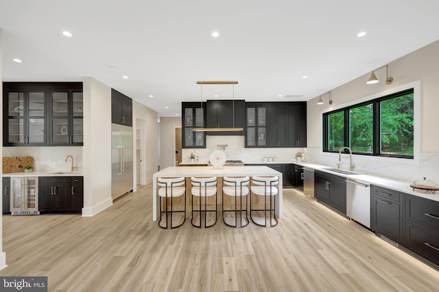 1710 Fairview Ave, Mclean, VA 22101 - kitchen featuring appliances with stainless steel finishes, ventilation hood, backsplash, a kitchen bar, and light wood finished floors