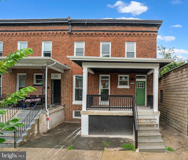 3002 Wylie Ave, Baltimore, MD 21215 - townhome / multi-family property with covered porch, brick siding, and stairs