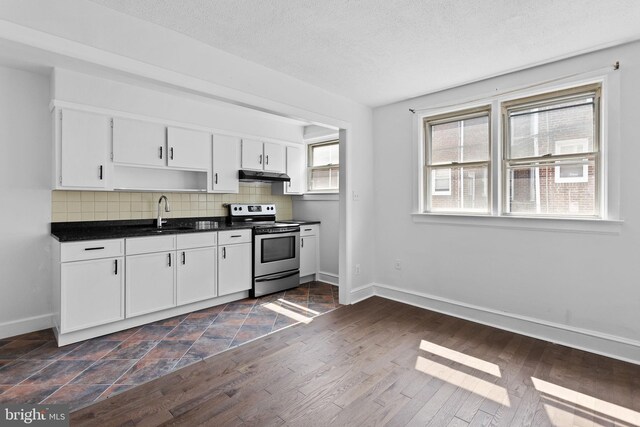 6333 Mershon St, Philadelphia, PA 19149 - kitchen featuring stainless steel electric range oven, under cabinet range hood, dark countertops, tasteful backsplash, and white cabinets