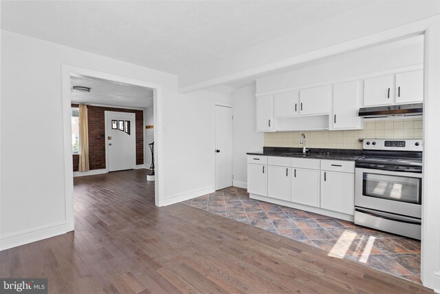 6333 Mershon St, Philadelphia, PA 19149 - kitchen with stainless steel electric stove, under cabinet range hood, dark countertops, tasteful backsplash, and white cabinetry