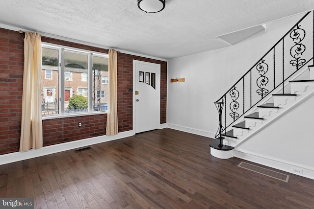 6333 Mershon St, Philadelphia, PA 19149 - foyer entrance with brick wall, a textured ceiling, wood finished floors, and stairway