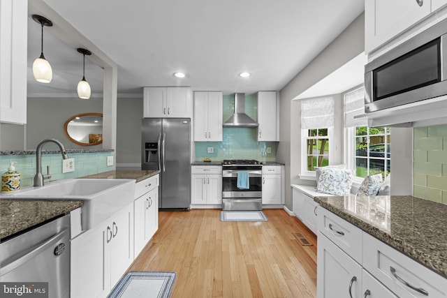 10034 Park Woods Ln, Burke, VA 22015 - kitchen featuring stainless steel appliances, wall chimney exhaust hood, decorative backsplash, white cabinets, and hanging light fixtures