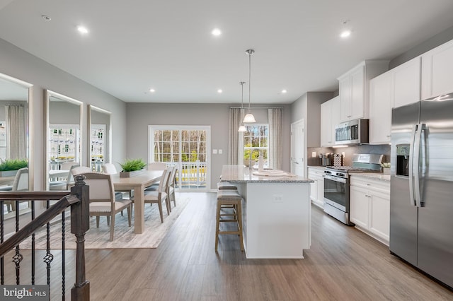 13626 Corinthian Ln Unit D-F02006D, Brandywine, MD 20613 - kitchen with appliances with stainless steel finishes, a kitchen island, white cabinetry, tasteful backsplash, and light stone countertops