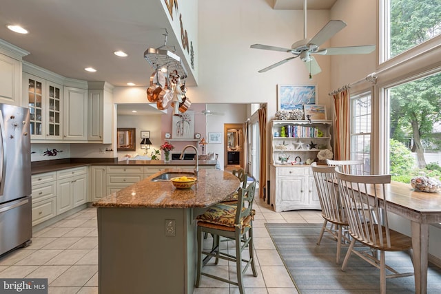 4 Surrey Rd, Rehoboth Beach, DE 19971 - kitchen featuring freestanding refrigerator, ceiling fan, a high ceiling, light tile patterned floors, and a kitchen breakfast bar