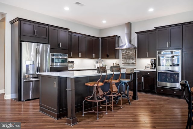 125 Towhee Dr, Lake Frederick, VA 22630 - kitchen with appliances with stainless steel finishes, wall chimney range hood, light countertops, a kitchen island, and dark wood-style flooring