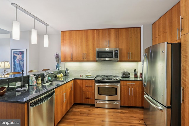 1425 Locust St Unit 7D, Philadelphia, PA 19102 - kitchen featuring appliances with stainless steel finishes, a peninsula, brown cabinetry, decorative backsplash, and wood finished floors