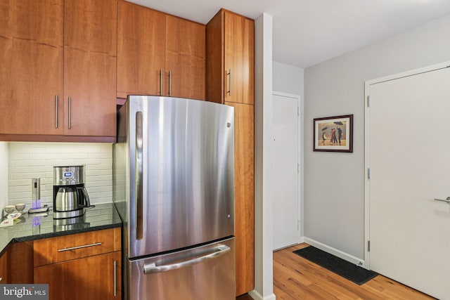 1425 Locust St Unit 7D, Philadelphia, PA 19102 - kitchen featuring freestanding refrigerator, wood finished floors, decorative backsplash, dark stone counters, and brown cabinetry