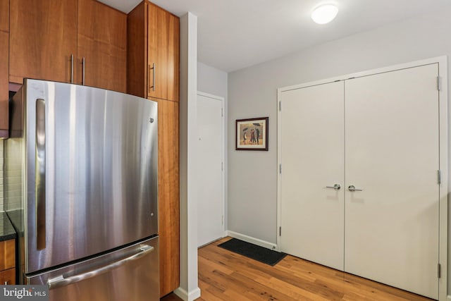 1425 Locust St Unit 7D, Philadelphia, PA 19102 - kitchen featuring freestanding refrigerator, light wood-type flooring, brown cabinetry, dark countertops, and modern cabinets