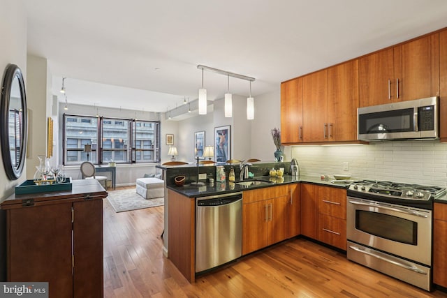 1425 Locust St Unit 7D, Philadelphia, PA 19102 - kitchen with appliances with stainless steel finishes, open floor plan, brown cabinetry, decorative backsplash, and a peninsula