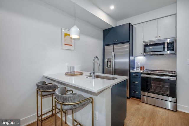 2310 4th St NE Unit B5, Washington, DC 20002 - kitchen featuring appliances with stainless steel finishes, blue cabinetry, a peninsula, and light wood-style flooring