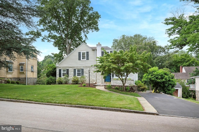12 Rodney Rd, Bryn Mawr, PA 19010 - view of front of house with stone siding, a front yard, a chimney, and driveway