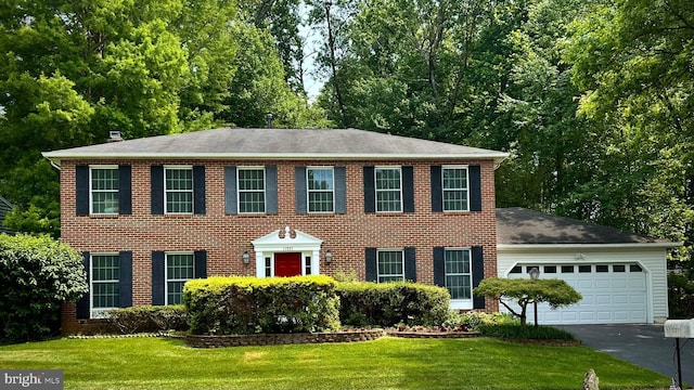 11531 Paramus Dr, North Potomac, MD 20878 - colonial house featuring a garage, asphalt driveway, a front lawn, and brick siding