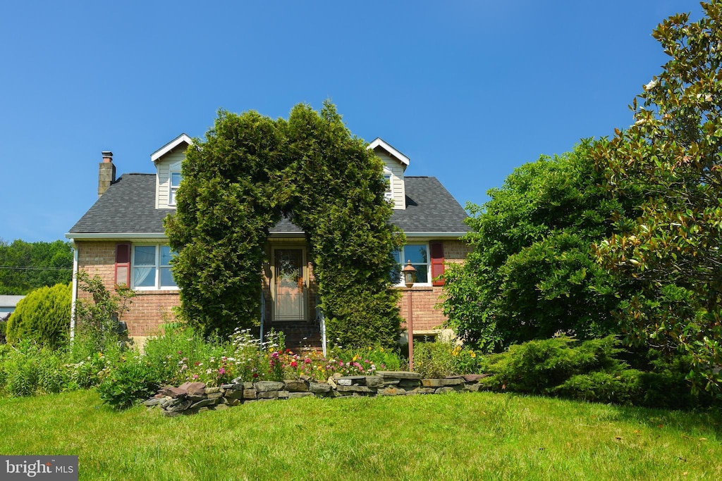 1365 N State St, Pottstown, PA 19464 - obstructed view of property with brick siding, a chimney, a front yard, and a shingled roof