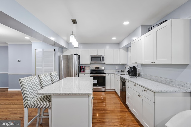 9126 Fisteris Ct, Springfield, VA 22152 - kitchen featuring stainless steel appliances, a kitchen bar, a center island, wood finished floors, and recessed lighting