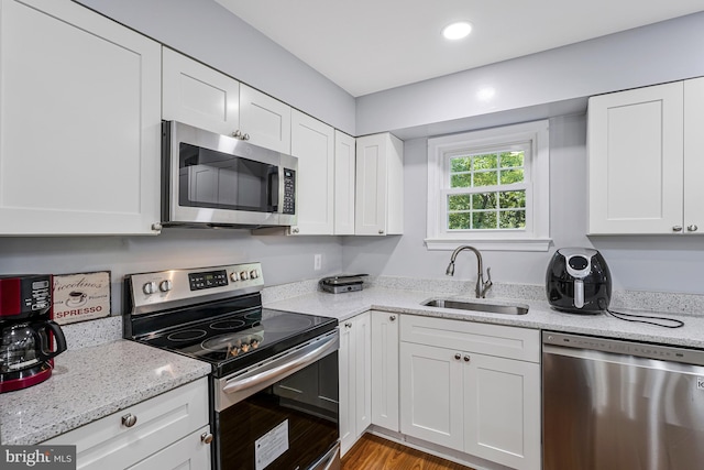 9126 Fisteris Ct, Springfield, VA 22152 - kitchen with appliances with stainless steel finishes, white cabinets, light stone countertops, wood finished floors, and recessed lighting