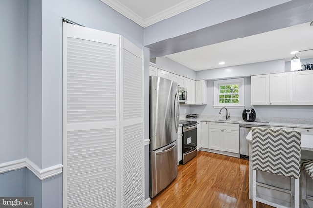 9126 Fisteris Ct, Springfield, VA 22152 - kitchen featuring appliances with stainless steel finishes, ornamental molding, wood finished floors, white cabinets, and light stone countertops