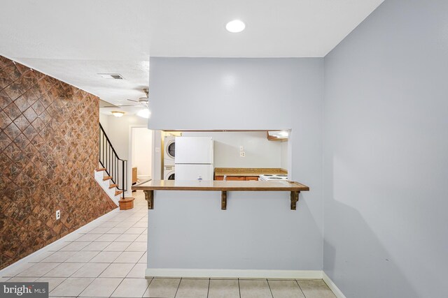 9126 Fisteris Ct, Springfield, VA 22152 - kitchen with stacked washer / dryer, freestanding refrigerator, light tile patterned flooring, ceiling fan, and a peninsula