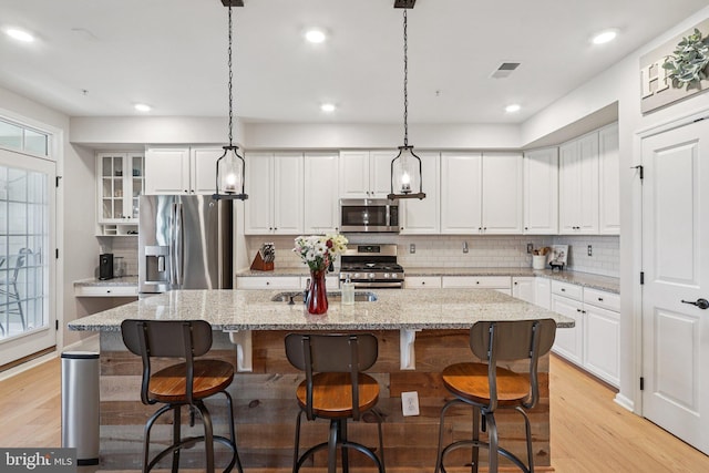 269 High Rail Ter SE, Leesburg, VA 20175 - kitchen with appliances with stainless steel finishes, tasteful backsplash, light wood-style floors, an island with sink, and white cabinetry