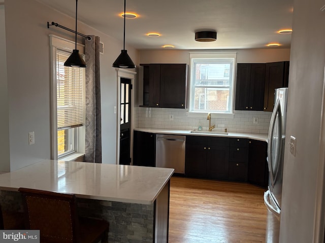 643 Jamestown Ave, Philadelphia, PA 19128 - kitchen featuring stainless steel appliances, light wood finished floors, tasteful backsplash, a peninsula, and decorative light fixtures
