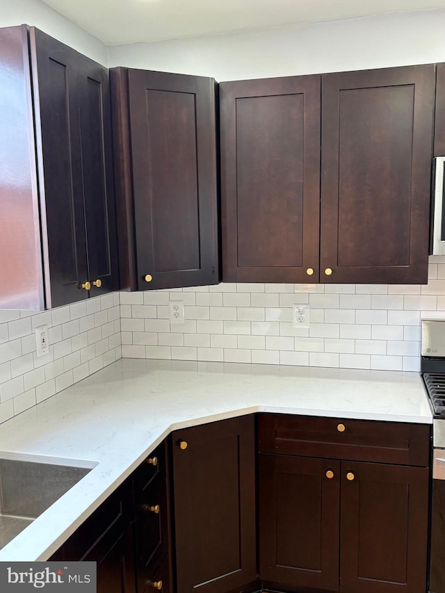 643 Jamestown Ave, Philadelphia, PA 19128 - kitchen featuring tasteful backsplash, light stone counters, dark brown cabinets, and stainless steel gas range