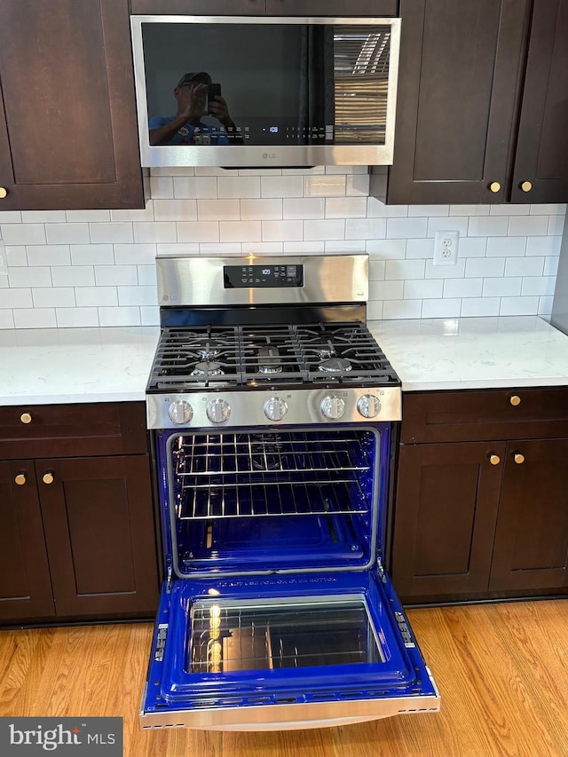 643 Jamestown Ave, Philadelphia, PA 19128 - kitchen featuring stainless steel gas stove, dark brown cabinets, light countertops, light wood finished floors, and backsplash