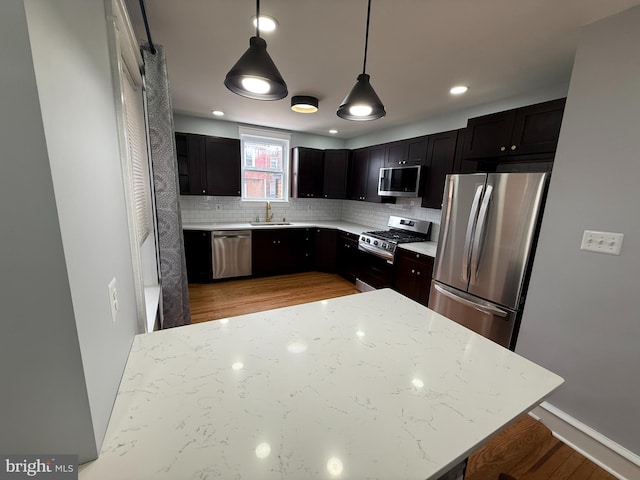 643 Jamestown Ave, Philadelphia, PA 19128 - kitchen featuring appliances with stainless steel finishes, decorative backsplash, light wood-type flooring, pendant lighting, and light stone counters