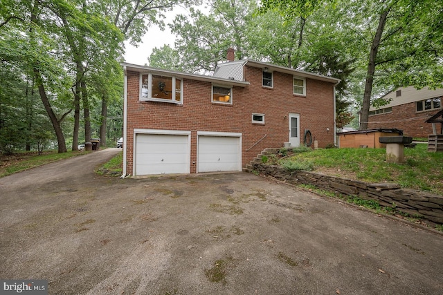 643 Crestwood Rd, Wayne, PA 19087 - view of side of home featuring driveway, brick siding, an attached garage, and a chimney