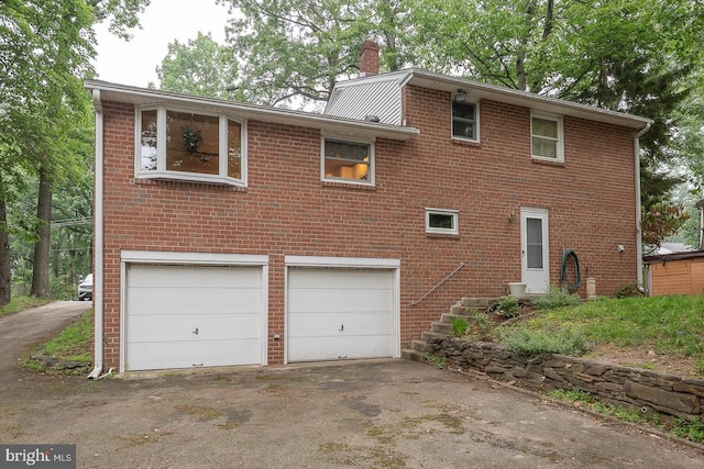 643 Crestwood Rd, Wayne, PA 19087 - view of front facade featuring an attached garage, brick siding, a chimney, and driveway