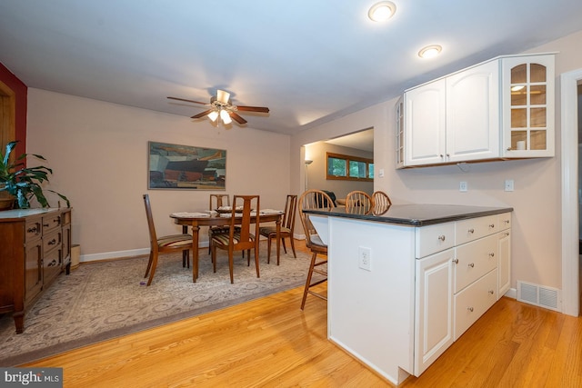 643 Crestwood Rd, Wayne, PA 19087 - kitchen featuring ceiling fan, white cabinets, a breakfast bar, glass insert cabinets, and light wood finished floors
