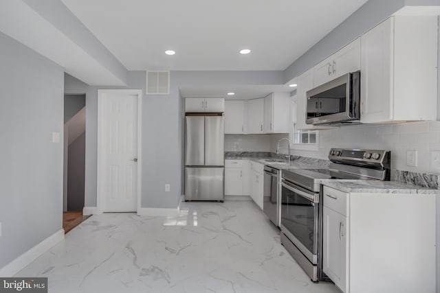 902 Nadine Ct, Landover, MD 20785 - kitchen with appliances with stainless steel finishes, white cabinetry, light marble finish flooring, decorative backsplash, and recessed lighting