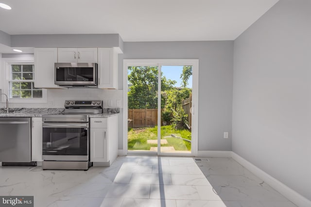 902 Nadine Ct, Landover, MD 20785 - kitchen with stainless steel appliances, light stone counters, light marble finish floors, white cabinets, and plenty of natural light