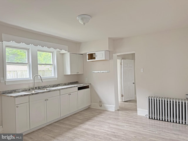 112 Dorman St, Harrington, DE 19952 - kitchen featuring radiator, light wood-type flooring, and white cabinetry