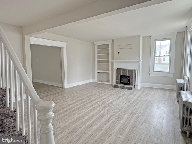 112 Dorman St, Harrington, DE 19952 - unfurnished living room with wood finished floors, stairs, built in shelves, a tiled fireplace, and radiator heating unit