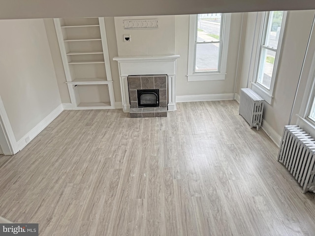 112 Dorman St, Harrington, DE 19952 - unfurnished living room with radiator heating unit, light wood finished floors, a tiled fireplace, and built in features