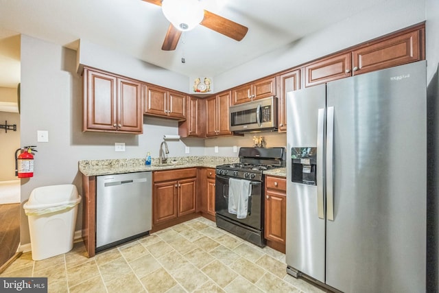 1043 Tristram Cir, Mantua, NJ 08051 - kitchen with appliances with stainless steel finishes, light stone counters, a ceiling fan, brown cabinets, and stone finish floors