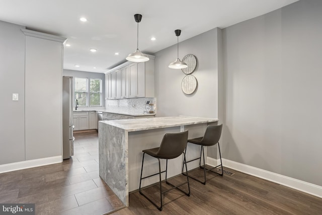 7357 E Walnut Ln, Philadelphia, PA 19138 - kitchen featuring a peninsula, light stone counters, a breakfast bar area, tasteful backsplash, and recessed lighting