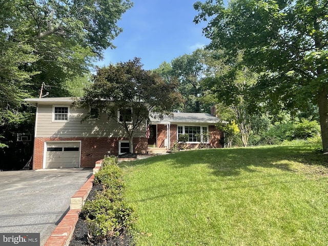 23244 Town Creek Dr, Lexington Park, MD 20653 - tri-level home featuring an attached garage, driveway, a front lawn, brick siding, and a chimney