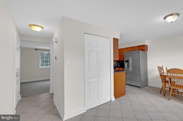 18659 Sandpiper Ln, Gaithersburg, MD 20879 - kitchen with stainless steel fridge, brown cabinets, light tile patterned floors, dark countertops, and decorative backsplash