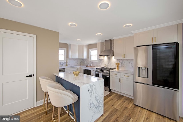 508 Vine St, Palmyra, NJ 08065 - kitchen featuring appliances with stainless steel finishes, wall chimney exhaust hood, a center island, light wood-type flooring, and recessed lighting